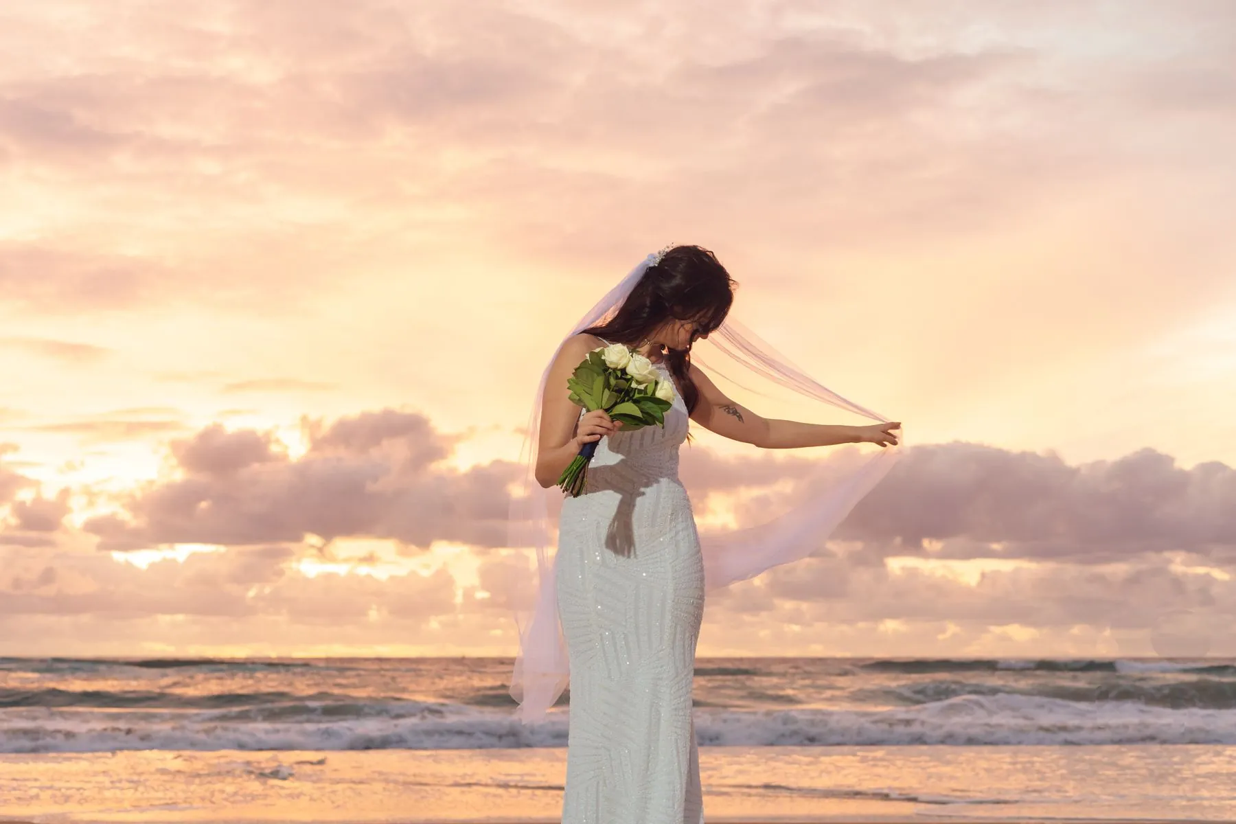 Bride with veil at sunset, beach wedding