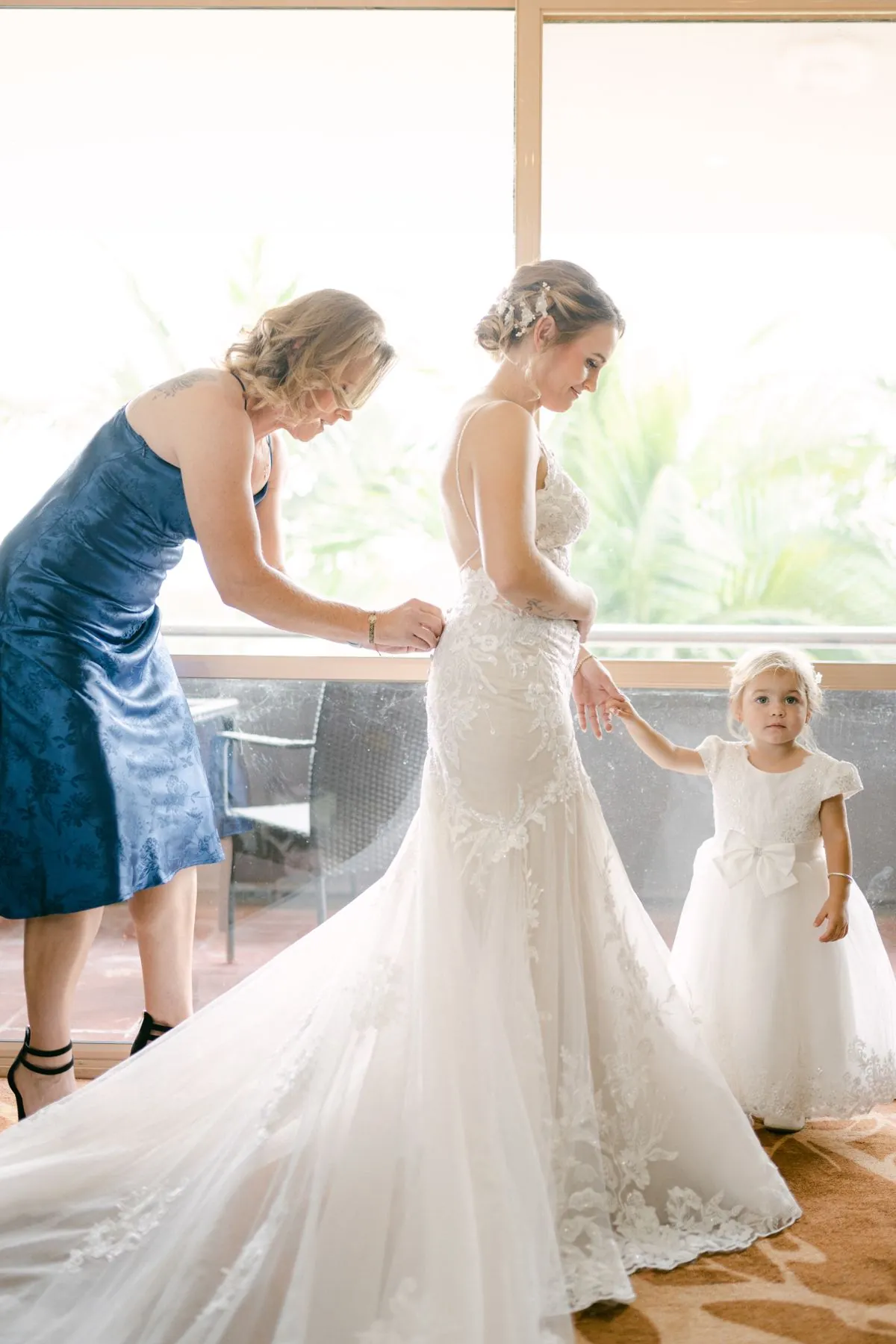 Bride getting into her dress with a flower girl